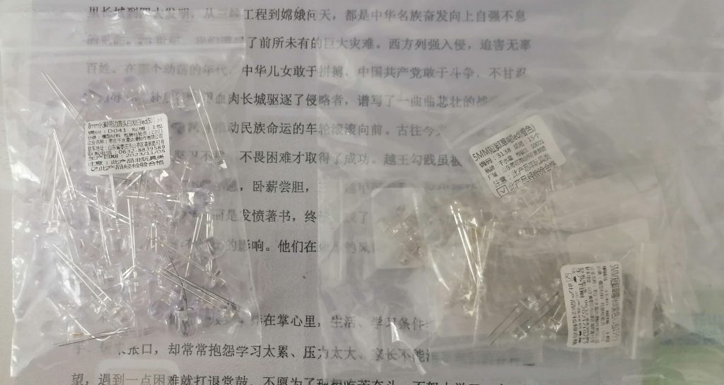 一大堆LED。左边的是50个8mm长脚带边圆头白发白LED，右边的是5mm短脚草帽的白发橙、白发紫、白发翠绿、白发黄、白发蓝、白发红LED各15个与15个5mm长脚草帽的白发粉红LED。